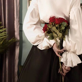 a victorian girl holding roses behind her back